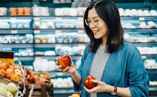 asian woman with glasses choosing apples at the supermarket
