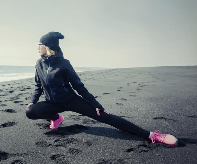 Woman stretching on beach winter