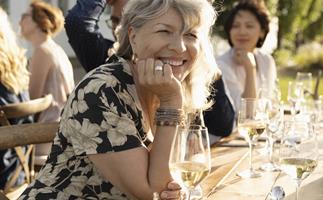 Smiling woman drinking wine at sunny garden party 