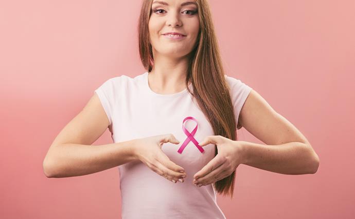 Woman holding hands in heart shape over breast