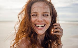 red headed woman smiling on a beach
