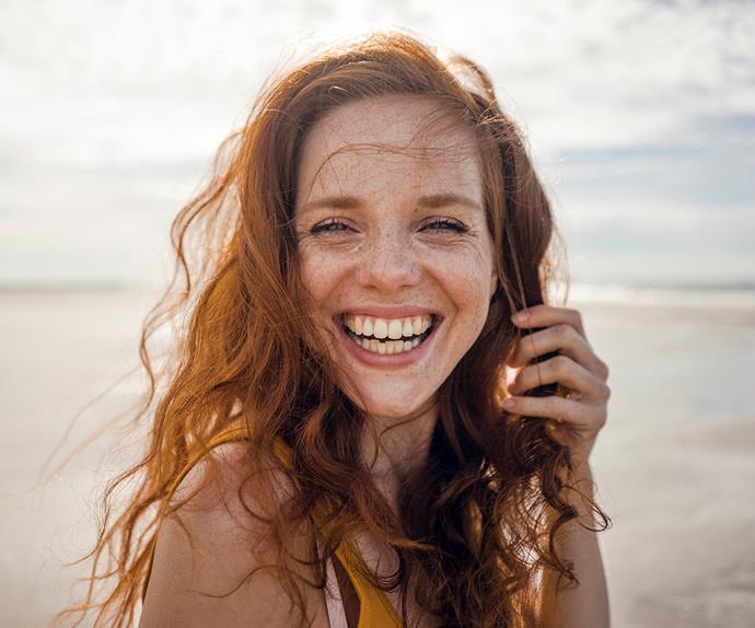 red headed woman smiling on a beach