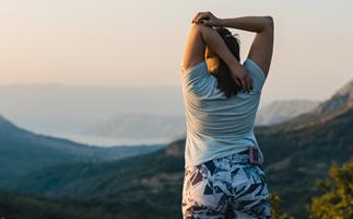 Woman with diabetes stretching on top of the hill