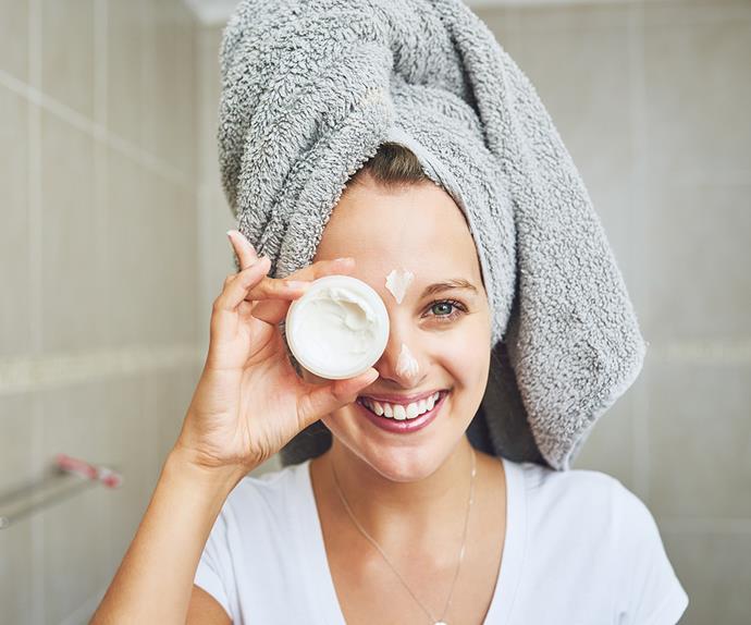 woman applying moisturiser happy