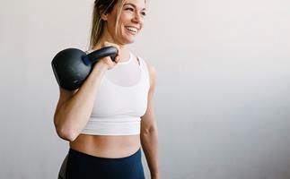 woman holding a kettle bell and smiling