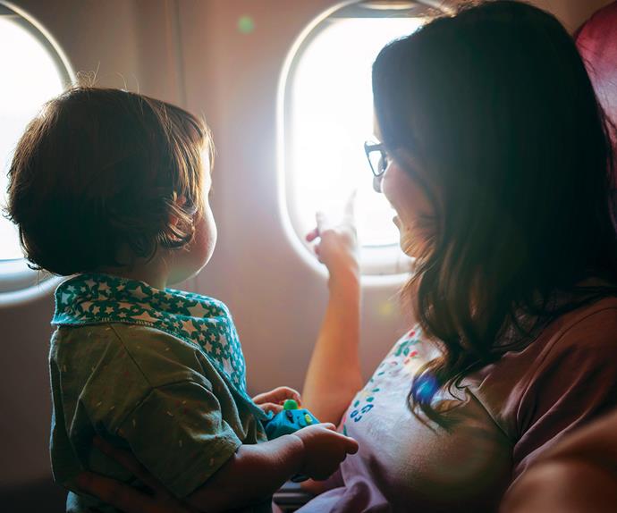 Mum and baby looking out window of plane