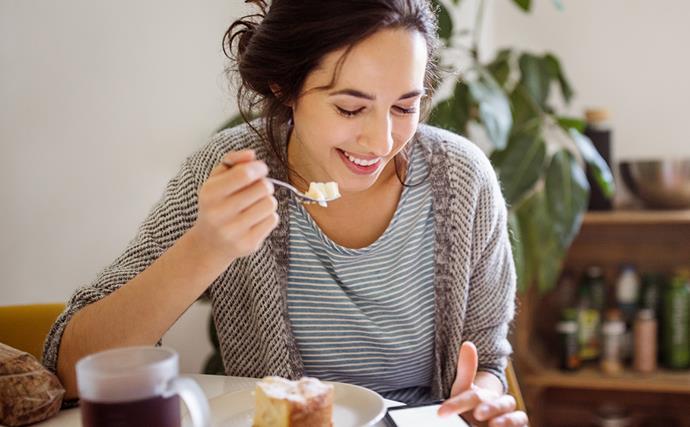 woman eating food looking at phone