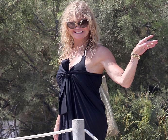 The ever-smiling Goldie Hawn radiates in a black swimsuit and matching sarong after a beach dip.